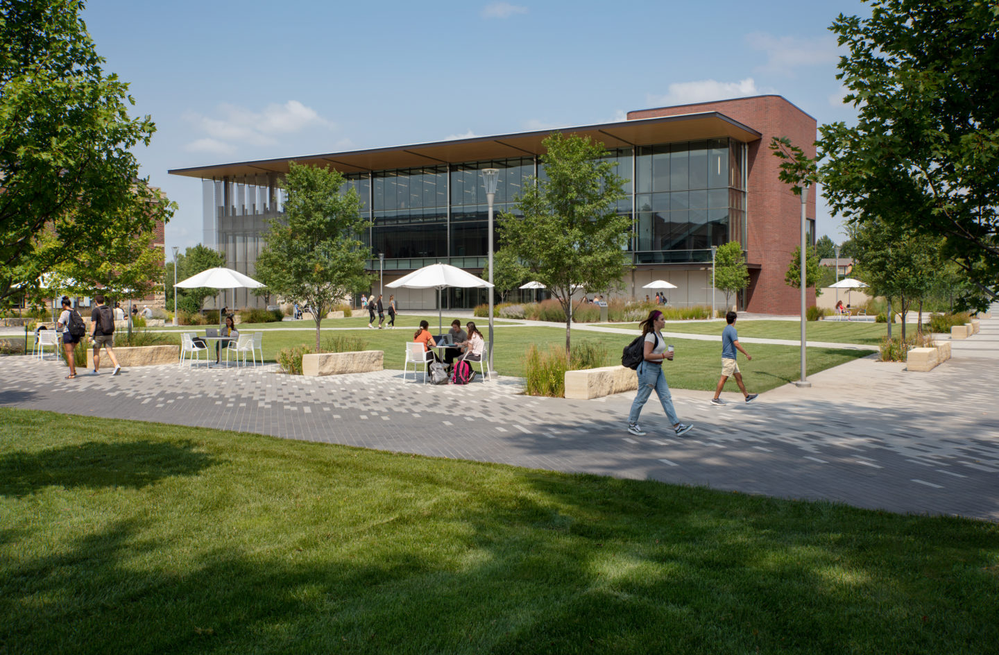 Exterior of the building shows the campus community. Students walking on the sidewalk out front.